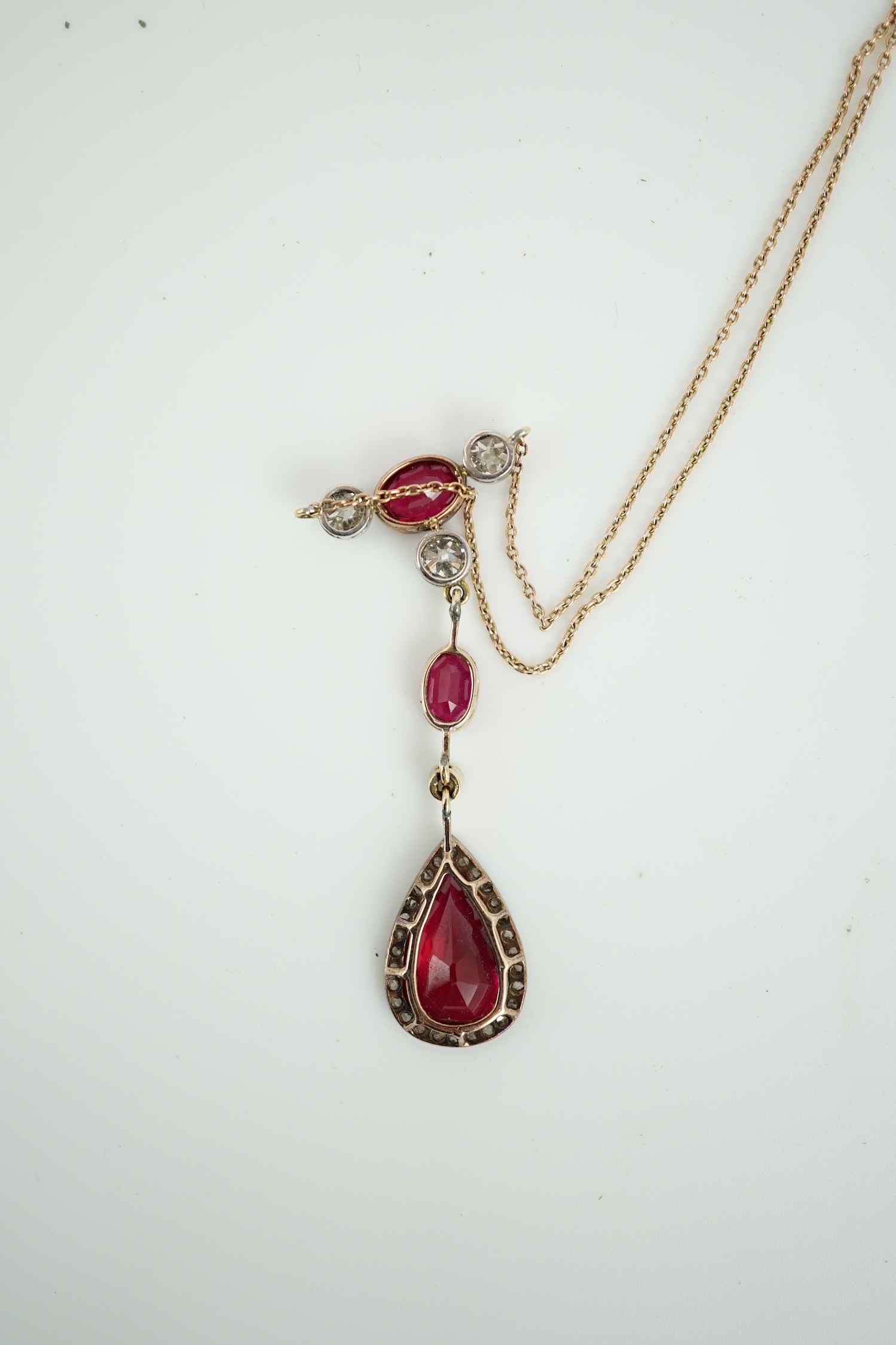 A 9ct, three stone synthetic ruby and four stone diamond set drop pendant necklace, pendant section 49mm, gross weight 5.2 gram.